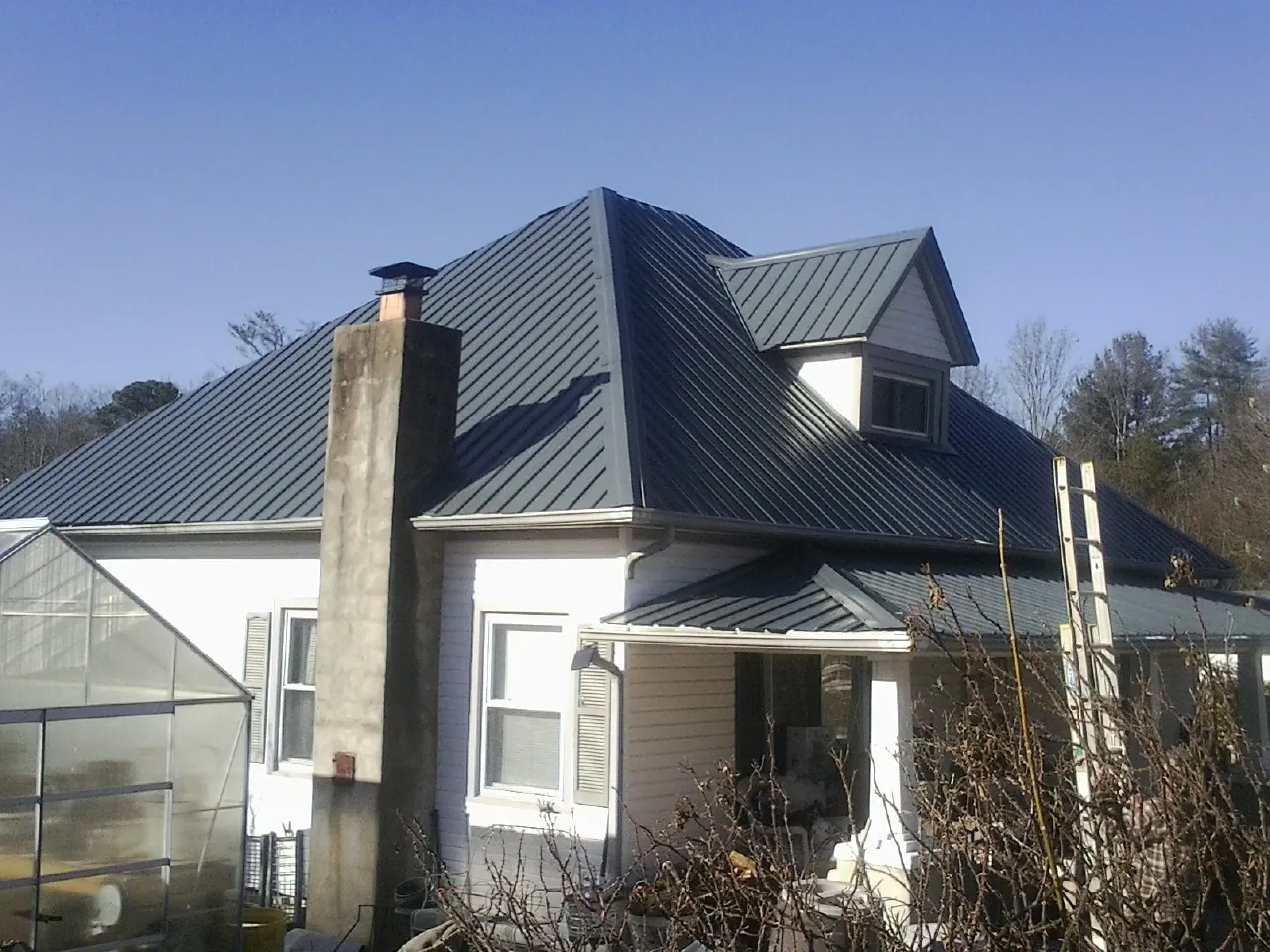 Dark blue standing seam metal roof on a white farmhouse with dormer — Slate & Tile Roof Repair by Roofing Brothers in Brunswick